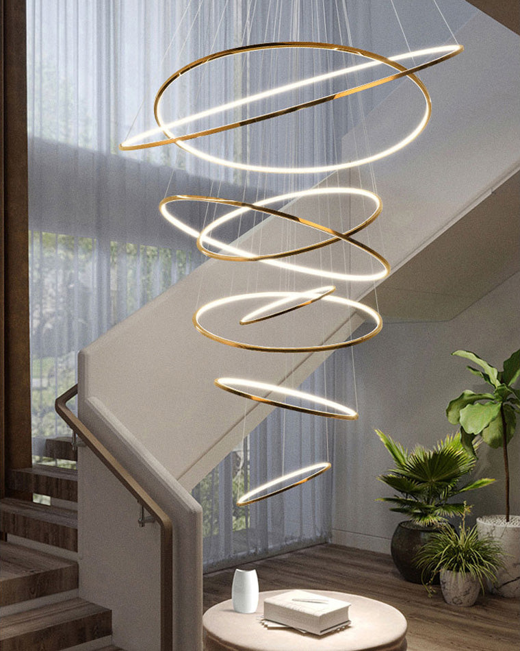 Warm entryway chandelier illuminating a double-height stairwell, drawing the eye upward while softening the emptiness of the open void.