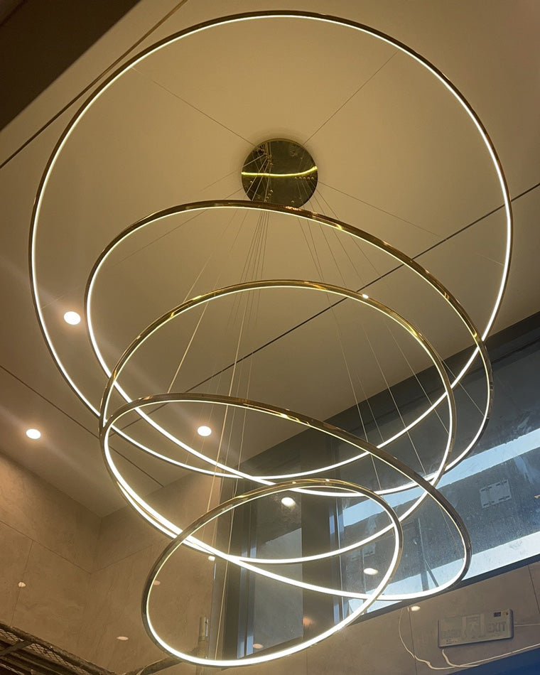 Upward close view of overlapping gold LED rings, emphasizing the chandelier’s immersive glow and floating visual effect.