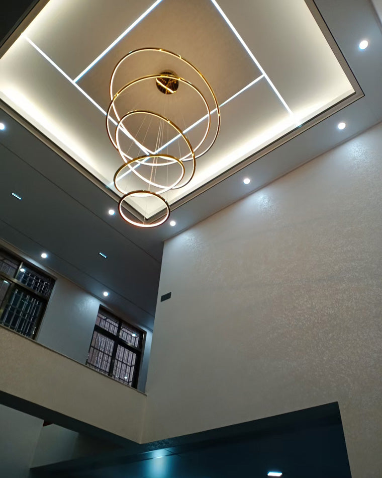 Gold entryway chandelier centered within a geometric cove ceiling, drawing attention upward and making the tall foyer feel intentionally designed.
