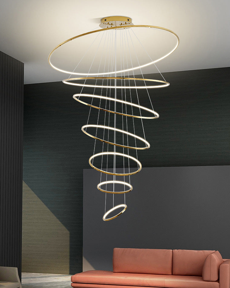 Tiered gold LED rings cascading above a modern sofa, balancing dramatic height with clean, contemporary elegance.