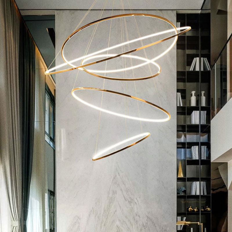 Five-ring gold entryway chandelier cascading beside a double-height library, adding sculptural light while preserving open sightlines.