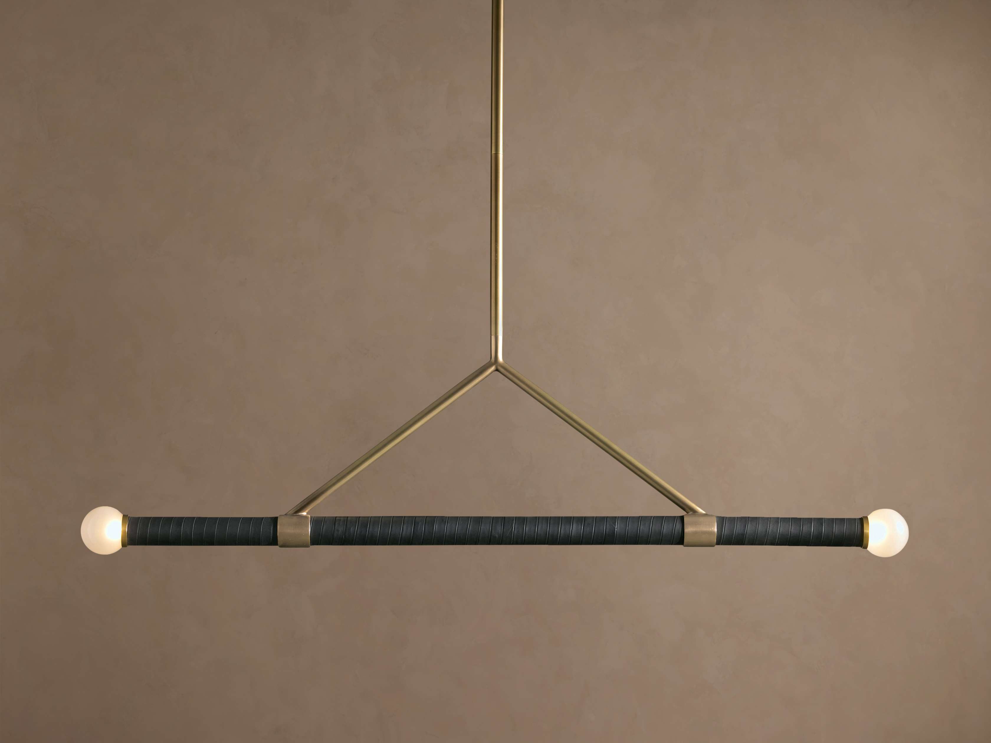 Randall Leather Pendant: Dark leather-wrapped horizontal bar with two frosted globe bulbs, suspended by a burnished brass frame.