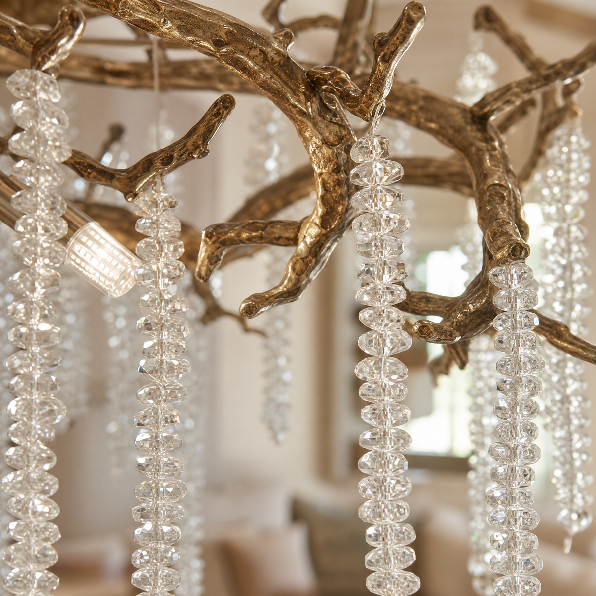 A circular antique gold branch chandelier with cascading crystal bead strands hangs from the ceiling in a lit room.