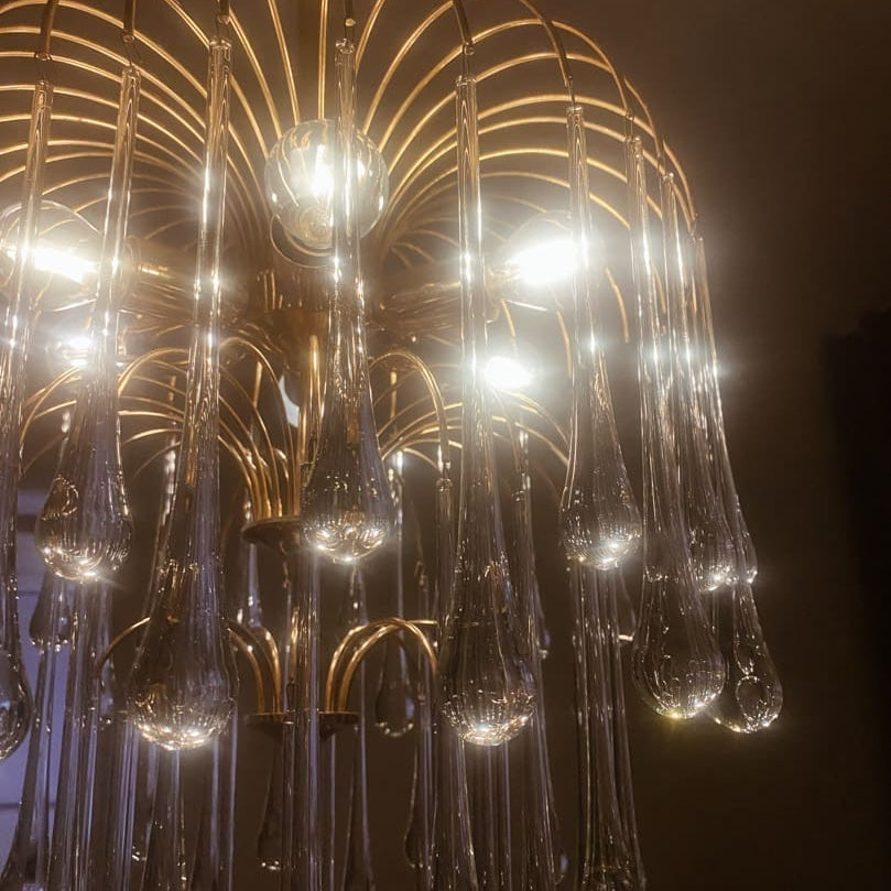 Gold chandelier with glass droplets against a dark background