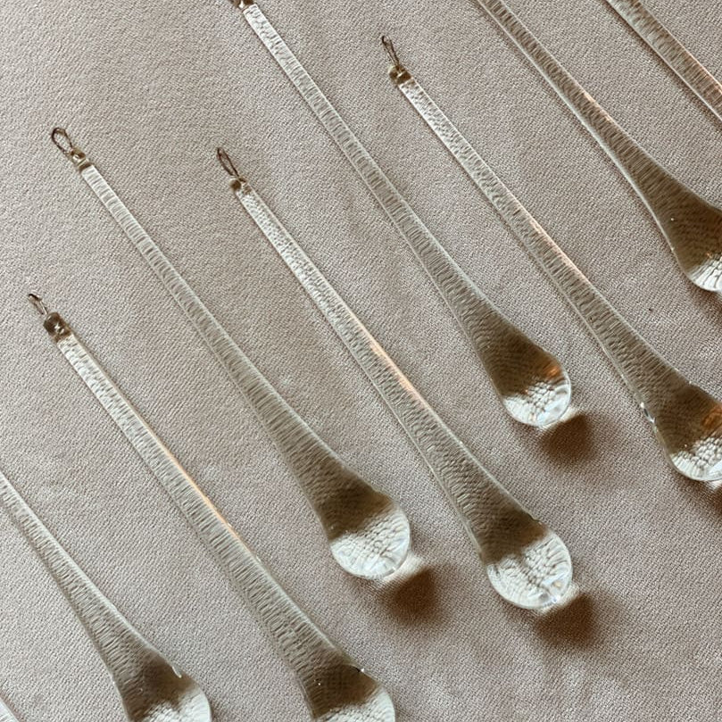 Set of metallic teardrop-shaped objects on a beige fabric background