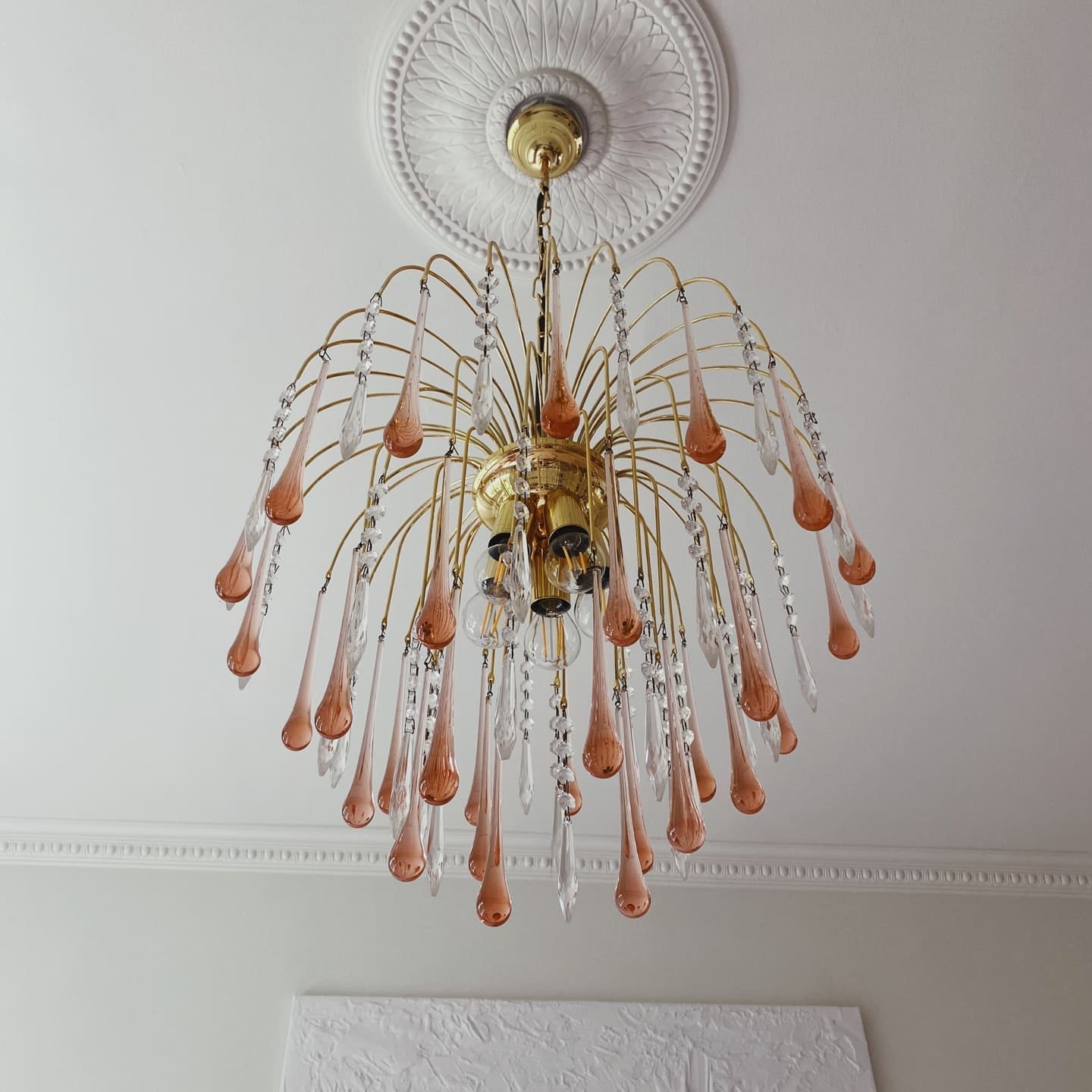 Decorative chandelier with pink and clear glass elements hanging from a white ceiling.