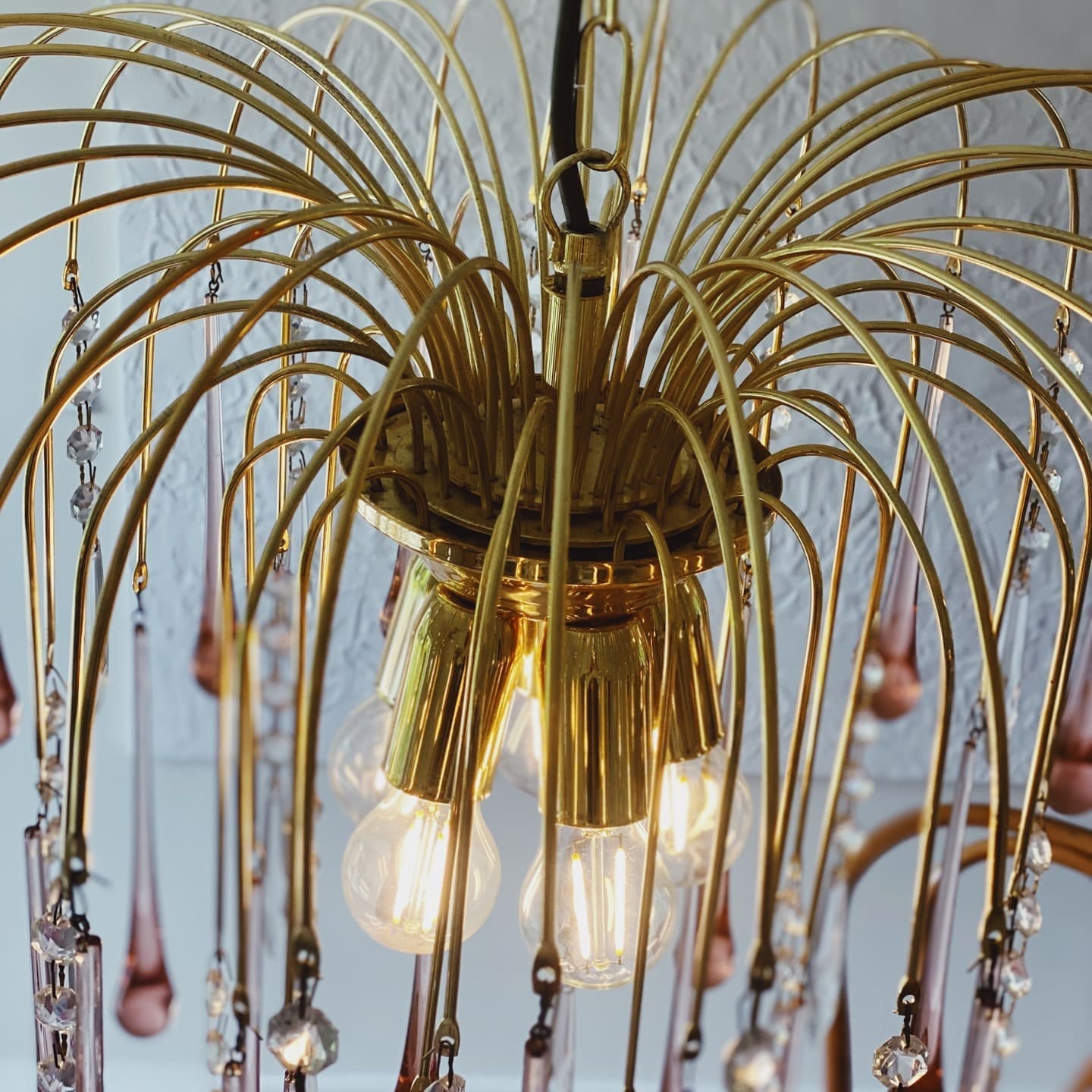Gold chandelier with hanging crystals against a white wall