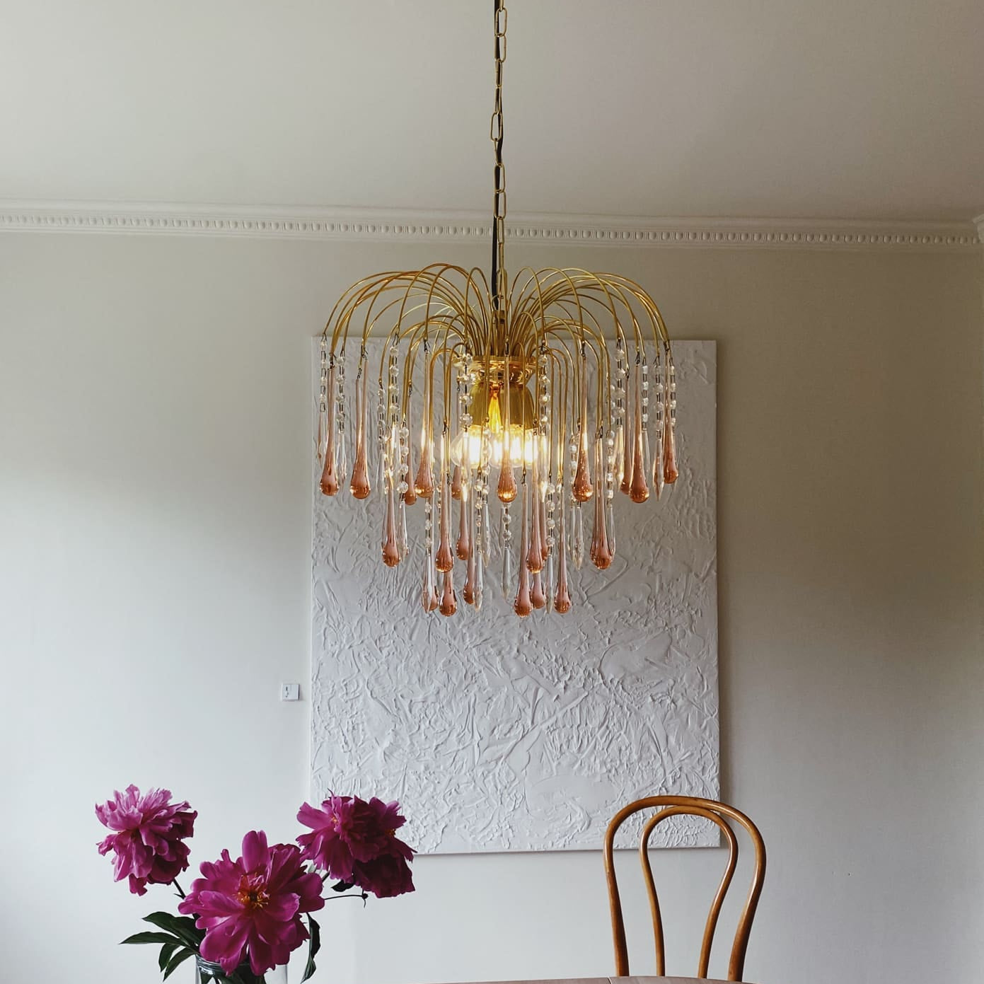 Chandelier hanging above a table with flowers in a room.