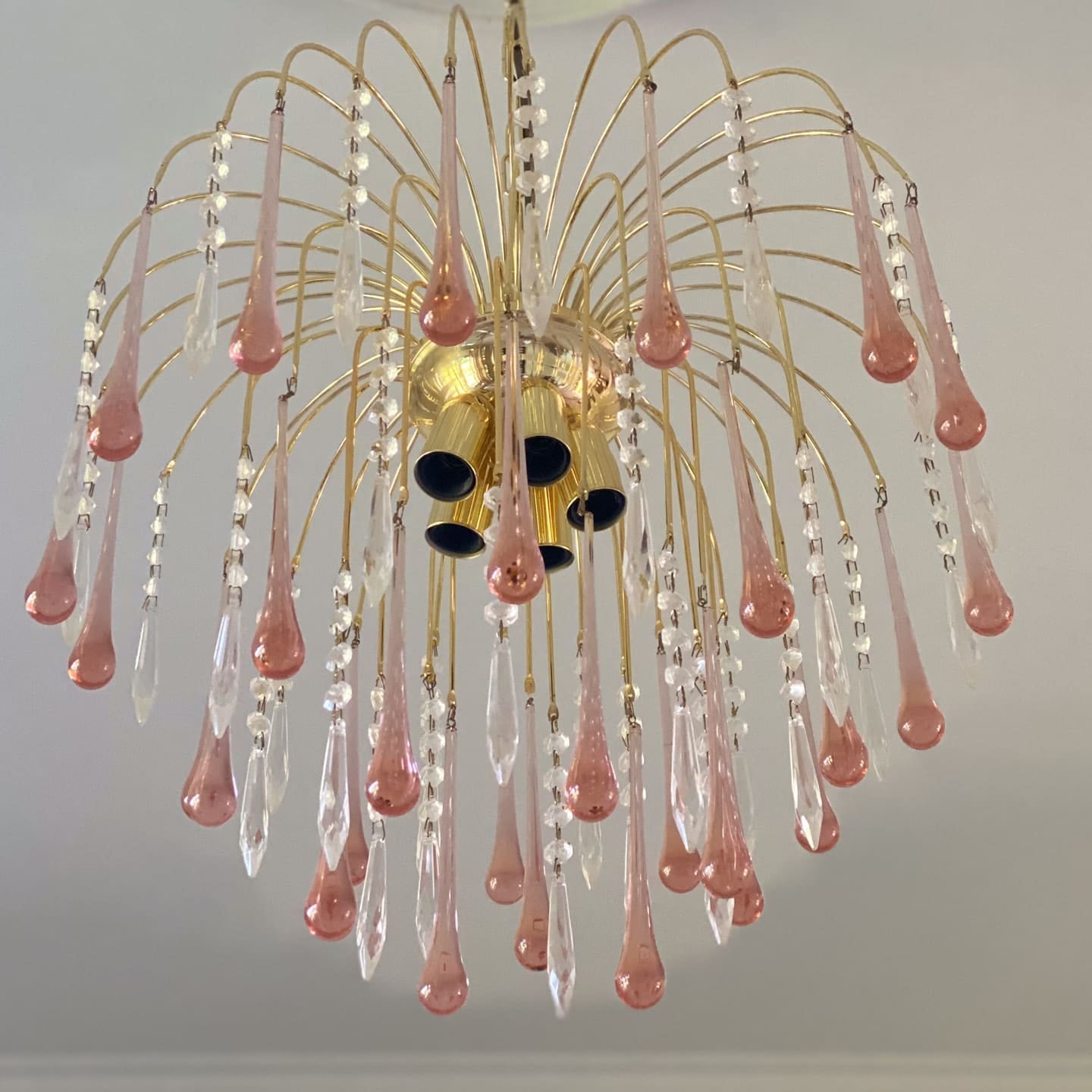 Chandelier with pink and clear glass droplets on a ceiling.