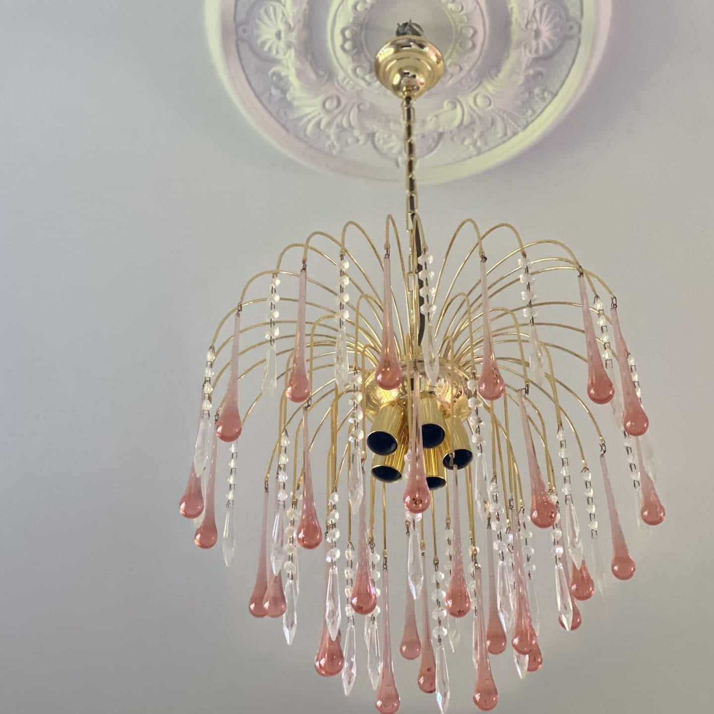 Decorative chandelier with pink and clear crystals on a ceiling with intricate design.