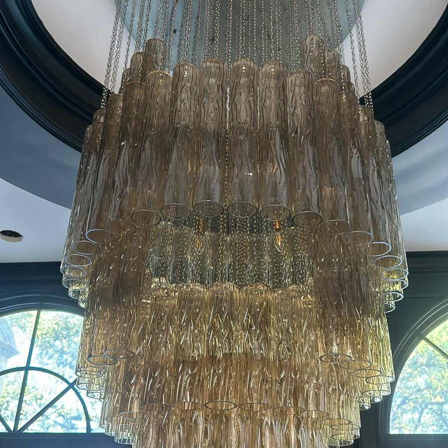 Large chandelier hanging from a ceiling with windows in the background