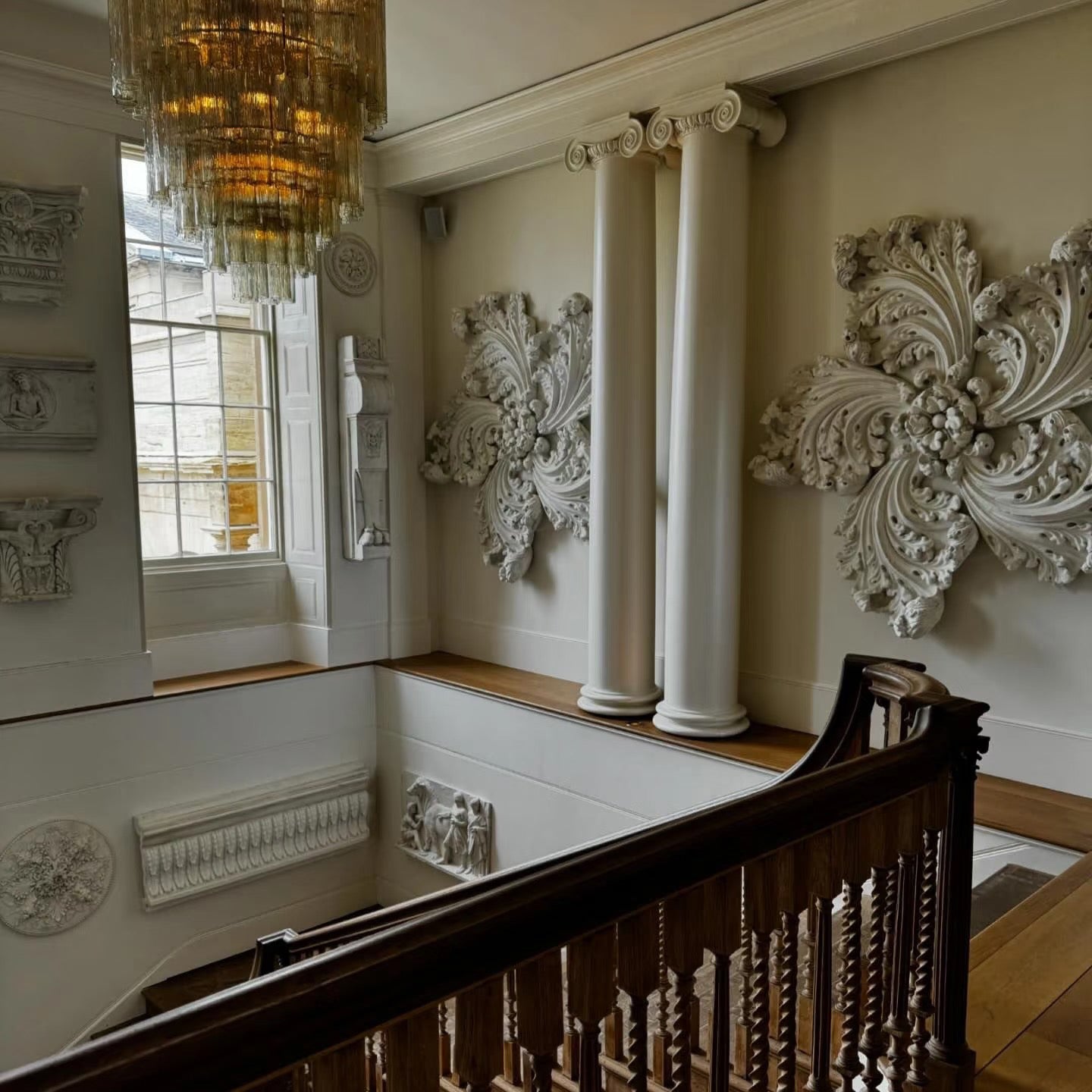 Decorative interior with ornate wall pieces, a chandelier, and a staircase.