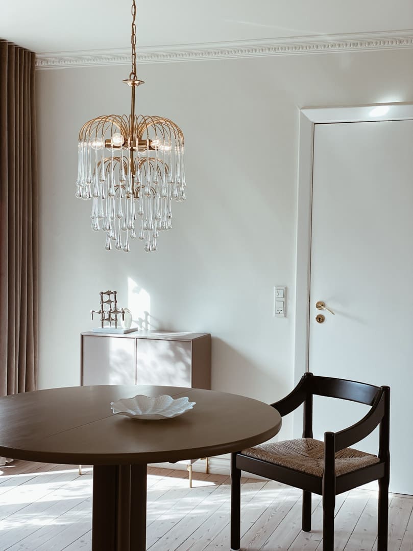 Dining room with a round table, chair, and decorative chandelier.