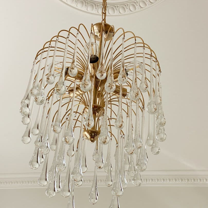 Gold chandelier with clear glass droplets on a decorative ceiling