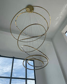Daylight view of the tiered gold chandelier, showing its sculptural ring composition even when the LEDs are switched off.