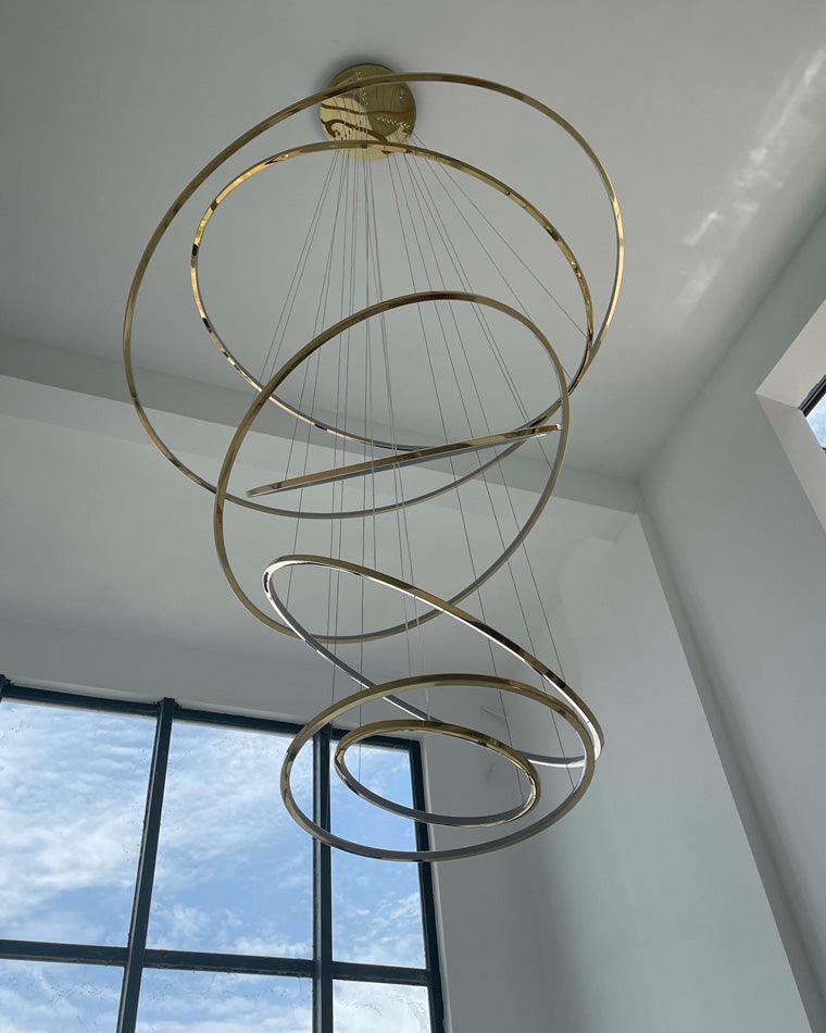 Daylight view of the tiered gold chandelier, showing its sculptural ring composition even when the LEDs are switched off.
