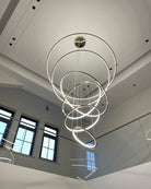 Glowing entryway chandelier suspended through a bright stair void, connecting the upper landing and lower floor with continuous light.