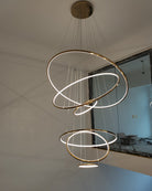 Seven-ring gold chandelier illuminating a newly finished stair void, creating an immediate focal point with minimal visual mass.