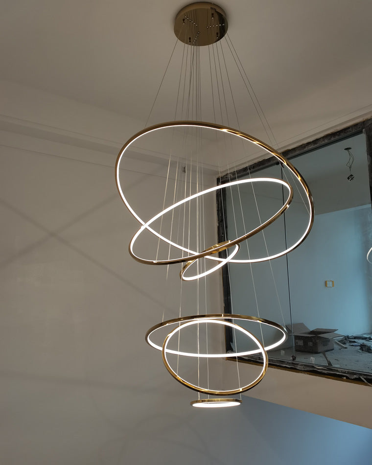 Seven-ring gold chandelier illuminating a newly finished stair void, creating an immediate focal point with minimal visual mass.