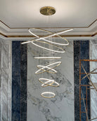 Fully illuminated gold ring chandelier against a marble feature wall, creating a luxurious centerpiece during the final installation stage.