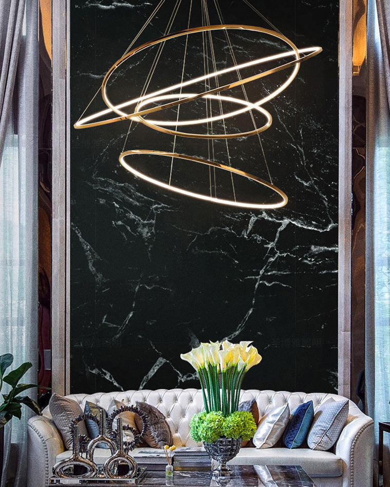 Golden ring chandelier glowing against black marble, adding warm contrast and visual depth without the heaviness of a traditional crystal fixture.