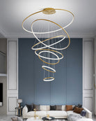 Large entryway chandelier filling a blue-paneled double-height wall with sweeping rings and even, glare-softened LED light.