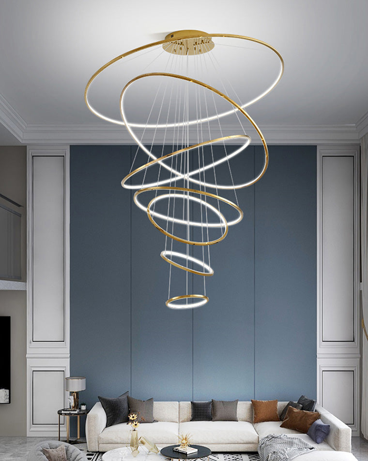 Large entryway chandelier filling a blue-paneled double-height wall with sweeping rings and even, glare-softened LED light.