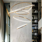 Five-ring gold entryway chandelier cascading beside a double-height library, adding sculptural light while preserving open sightlines.