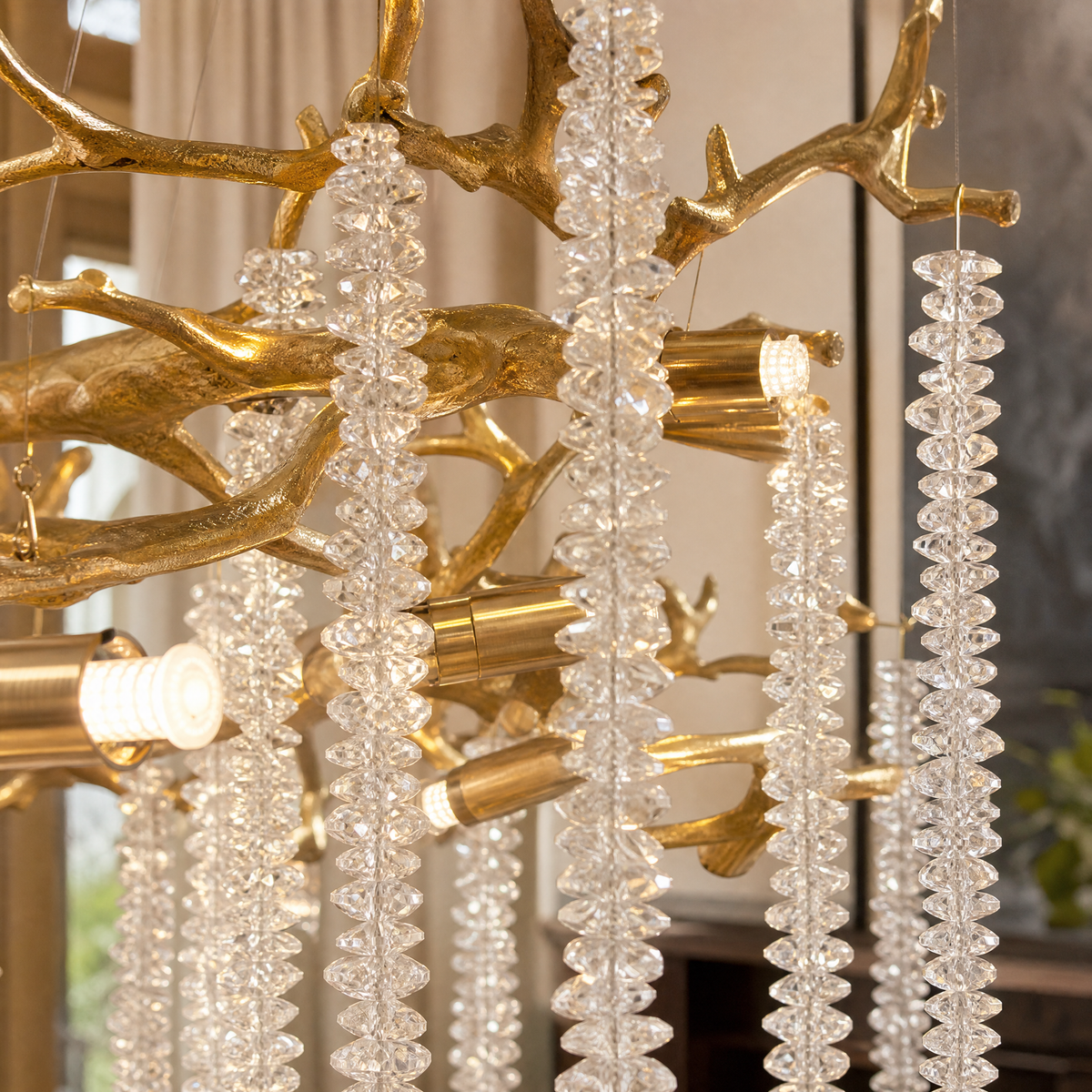 A Blush gold metal branch chandelier with cascading crystal beads suspended in a rainfall arrangement.