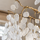 A modern organic branch chandelier with a warm gold metal frame and frosted white crystal petal accents.