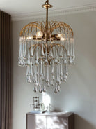 Gold chandelier with clear glass droplets in a room setting