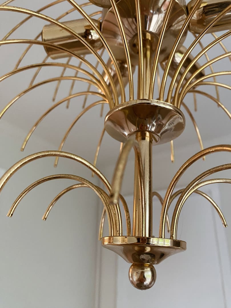 Gold chandelier with intricate design on a plain background