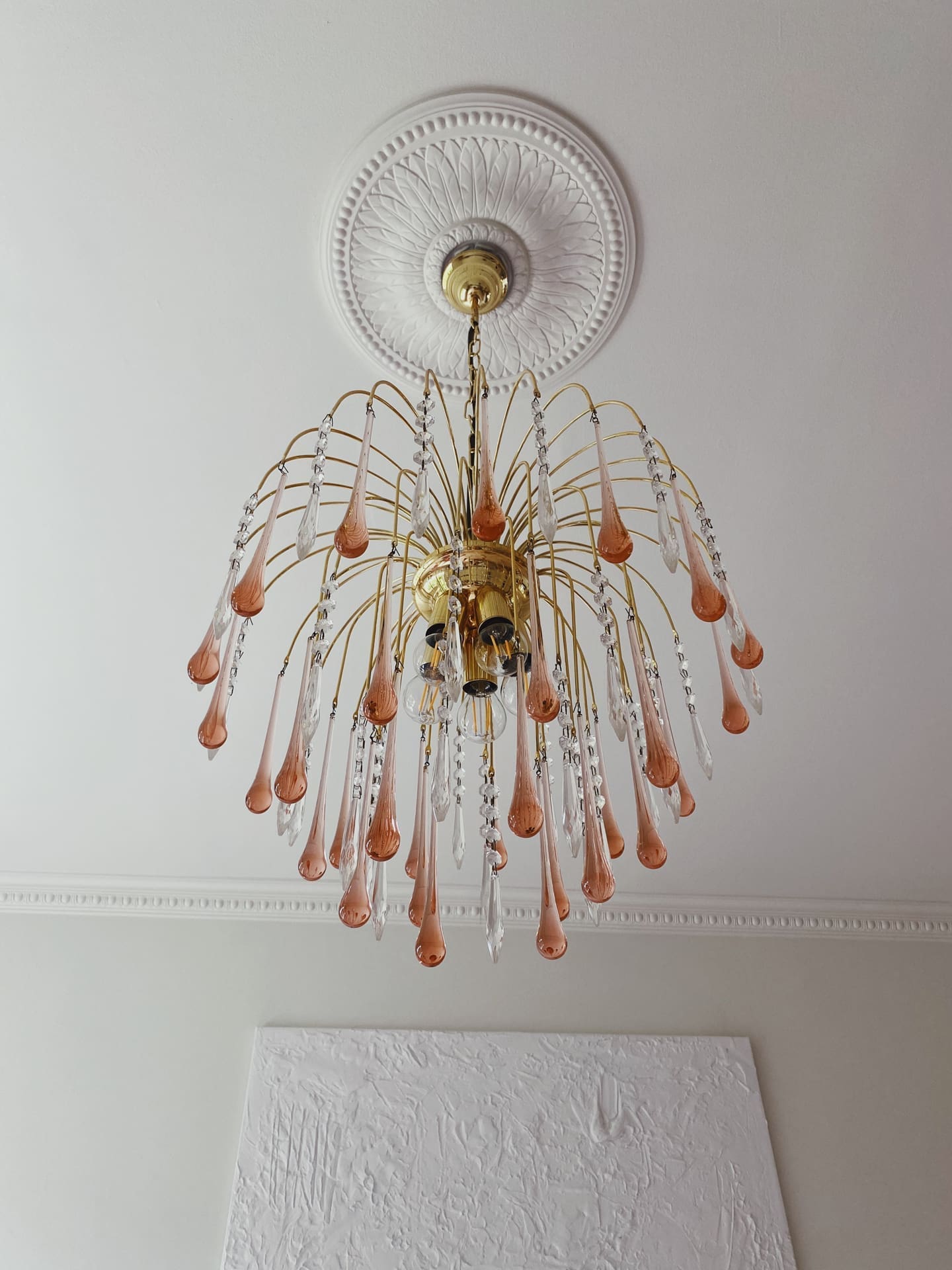 Decorative chandelier with pink and clear glass elements hanging from a white ceiling.