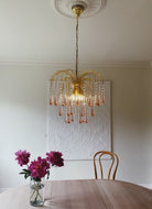 Chandelier hanging above a table with flowers in a room.