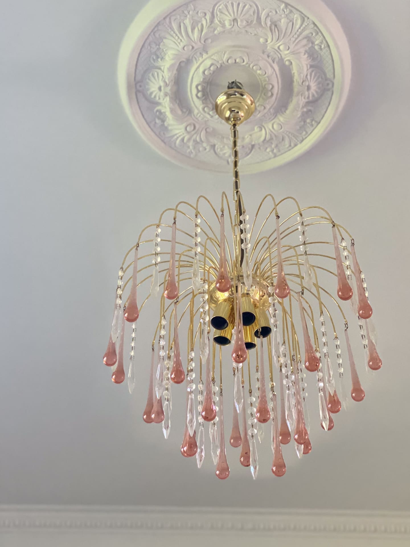 Decorative chandelier with pink and clear crystals on a ceiling with intricate design.