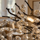 A modern matte black metal branch chandelier adorned with cascading clear crystal drops in a circular shape.