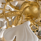 A long gold metal chandelier features white petal-shaped glass shades arranged in an organic branch silhouette.