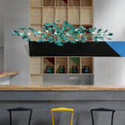Modern kitchen with a decorative chandelier, shelves with bottles, and stools.