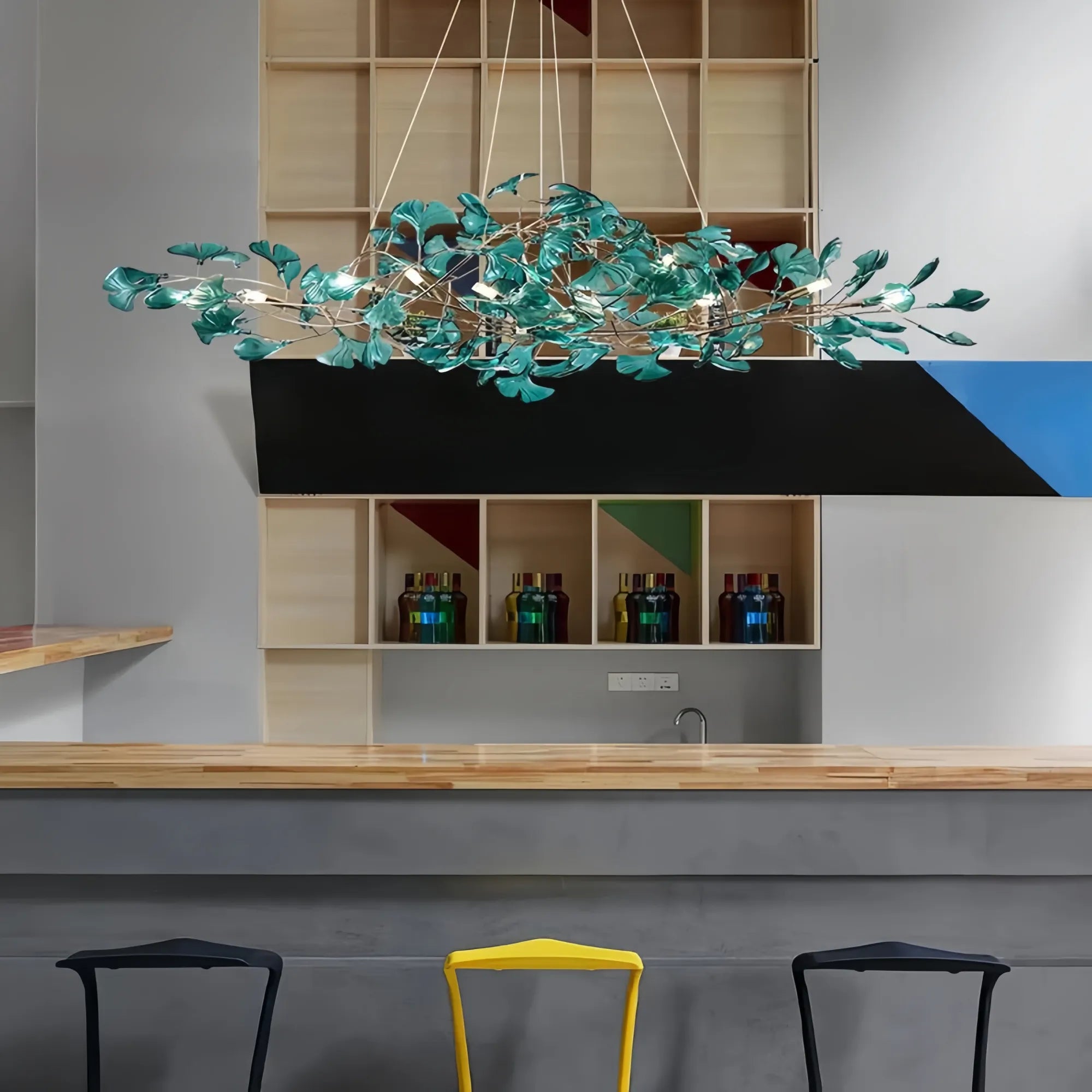 Modern kitchen with a decorative chandelier, shelves with bottles, and stools.
