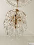 Gold chandelier with clear glass droplets on a decorative ceiling