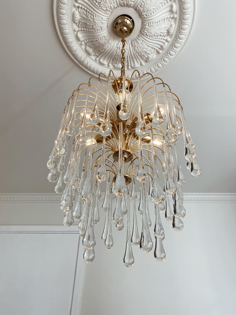 Decorative chandelier with crystal elements hanging from a ceiling.
